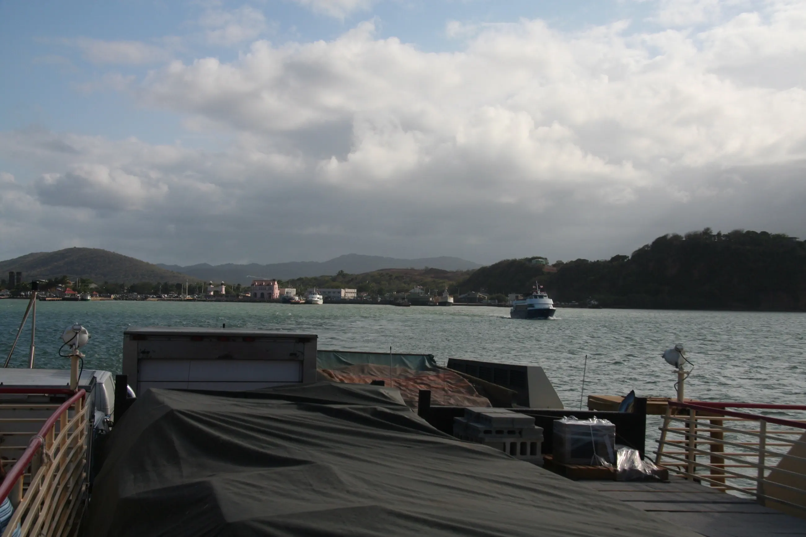 The loaded cargo deck of the Vieques ferry mid-crossing, with hills and a second ferry behind